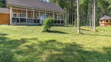A modern house with large windows, a wooden deck, and a small garden.