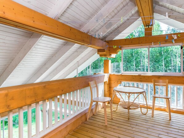 A wooden deck with a railing, a table, and two chairs.