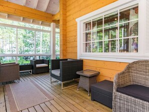 A covered outdoor seating area with wicker furniture and a view of the forest. - Katariina by Interhome (Juva)
