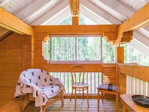 A wooden cabin with a covered porch, a dining table, and two chairs.