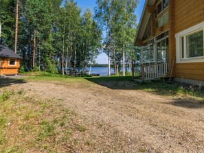 A cabin with a gravel driveway leading to a dock over water, surrounded by trees. - Katariina by Interhome (Juva)