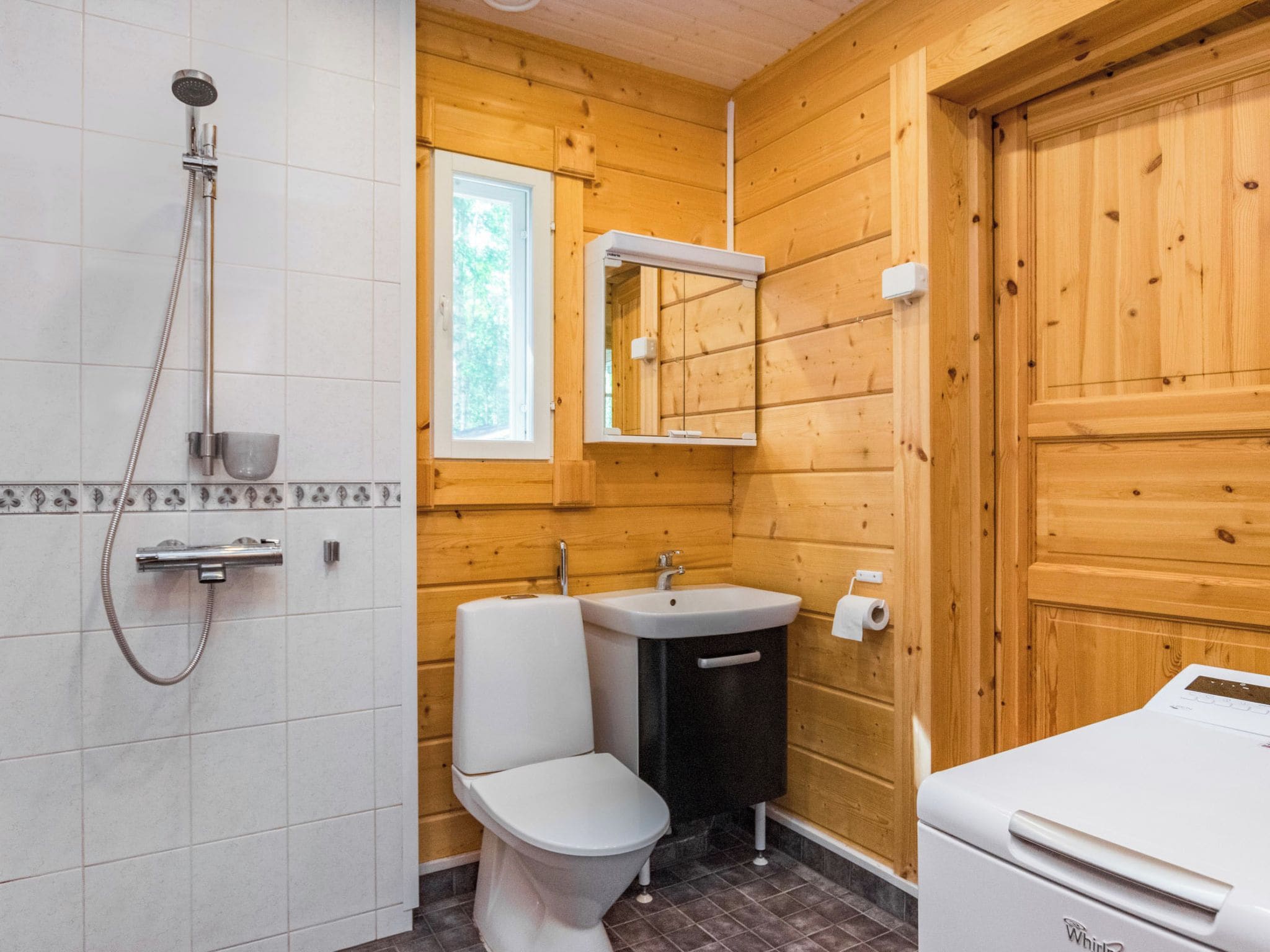 A bathroom with a shower, toilet, sink, and a mirror.