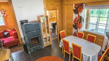 A cozy cabin interior with a fireplace, dining area, and a view of the outdoors.