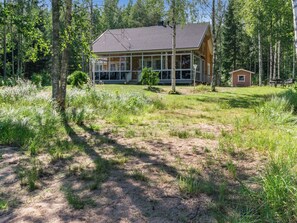 A cabin with a large glass front, surrounded by a forested area with a grassy yard. - Katariina by Interhome (Juva)