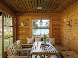 A wooden cabin interior with a table, benches, and a view of a lake. - Joutsenlahti by Interhome (Asikkala)