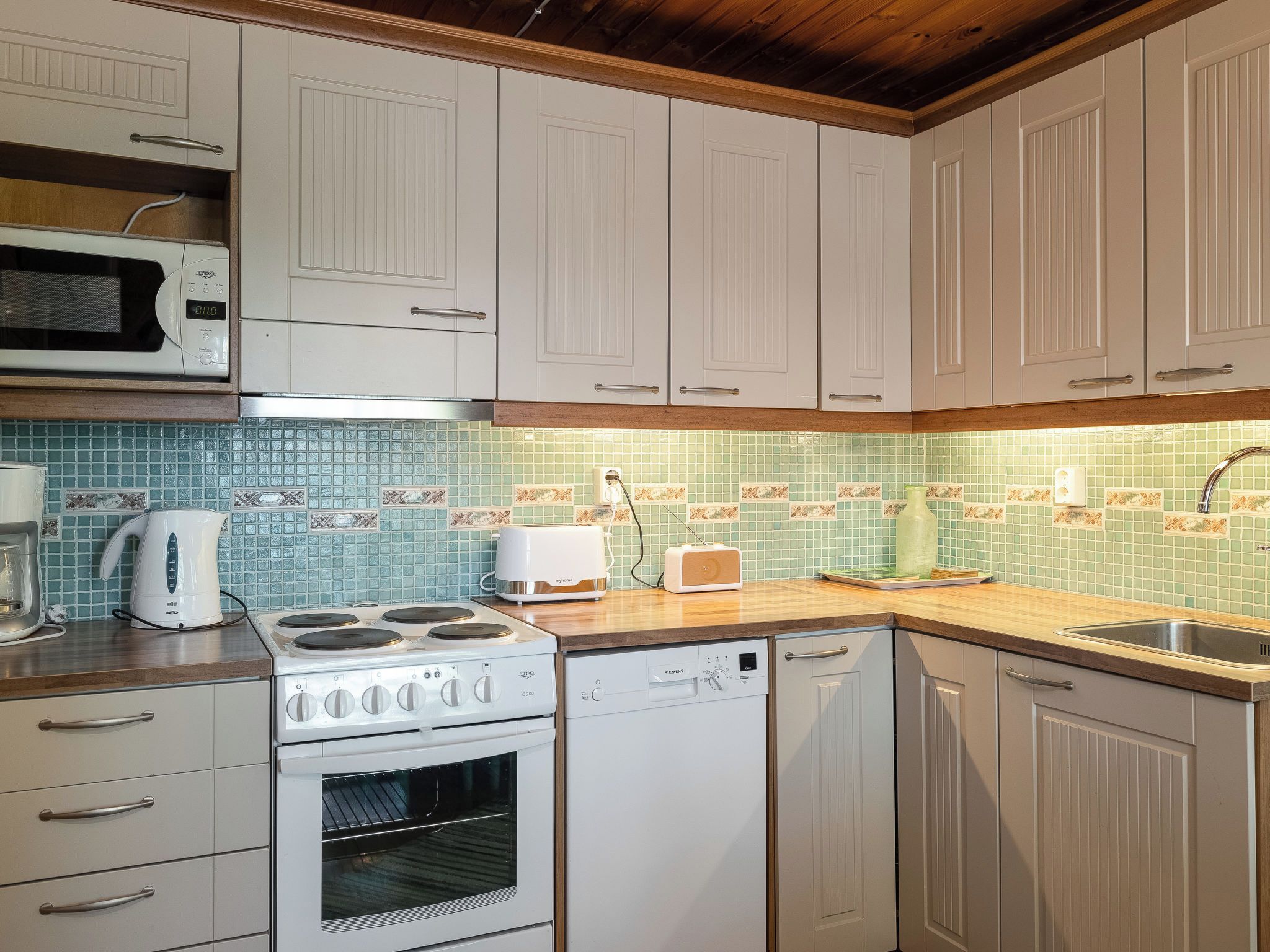 A kitchen with white cabinets, a microwave, a stove, a dishwasher, and a toaster.
