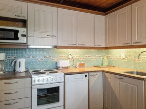 A kitchen with white cabinets, a microwave, a stove, a dishwasher, and a toaster. - Joutsenlahti by Interhome (Asikkala)