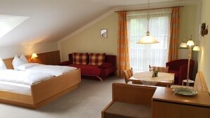 A hotel room with a bed, a sofa, a dining table, and a chair.