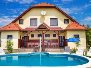Ein zweistöckiges Haus mit Schwimmbad davor.