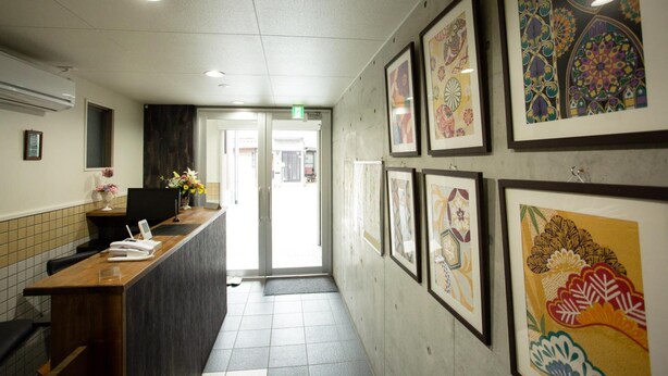 A reception area with a reception desk, framed artwork on the walls, and a tiled floor. - Rest inn Kyoto (Kyoto)