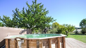 A wooden hot tub with a built-in heater, surrounded by a wooden deck and a grassy yard. - L' amandier by Interhome (Pernes les Fontaines)