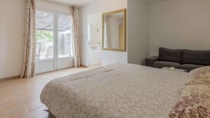 A bedroom with a large bed, a dresser, a mirror, and a sofa. - L' amandier by Interhome (Pernes les Fontaines)
