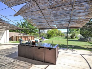 An outdoor patio area with a glass-top bar and wicker furniture, shaded by a pergola. - L' amandier by Interhome (Pernes les Fontaines)