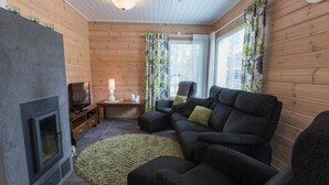 A cozy living room with a fireplace, a sofa, a TV, and a table with a lamp. - Pihkala 2 by Interhome (Äkäslompolo)