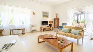 Uma sala de estar ampla com sofá, mesa de centro, televisão e lareira.
