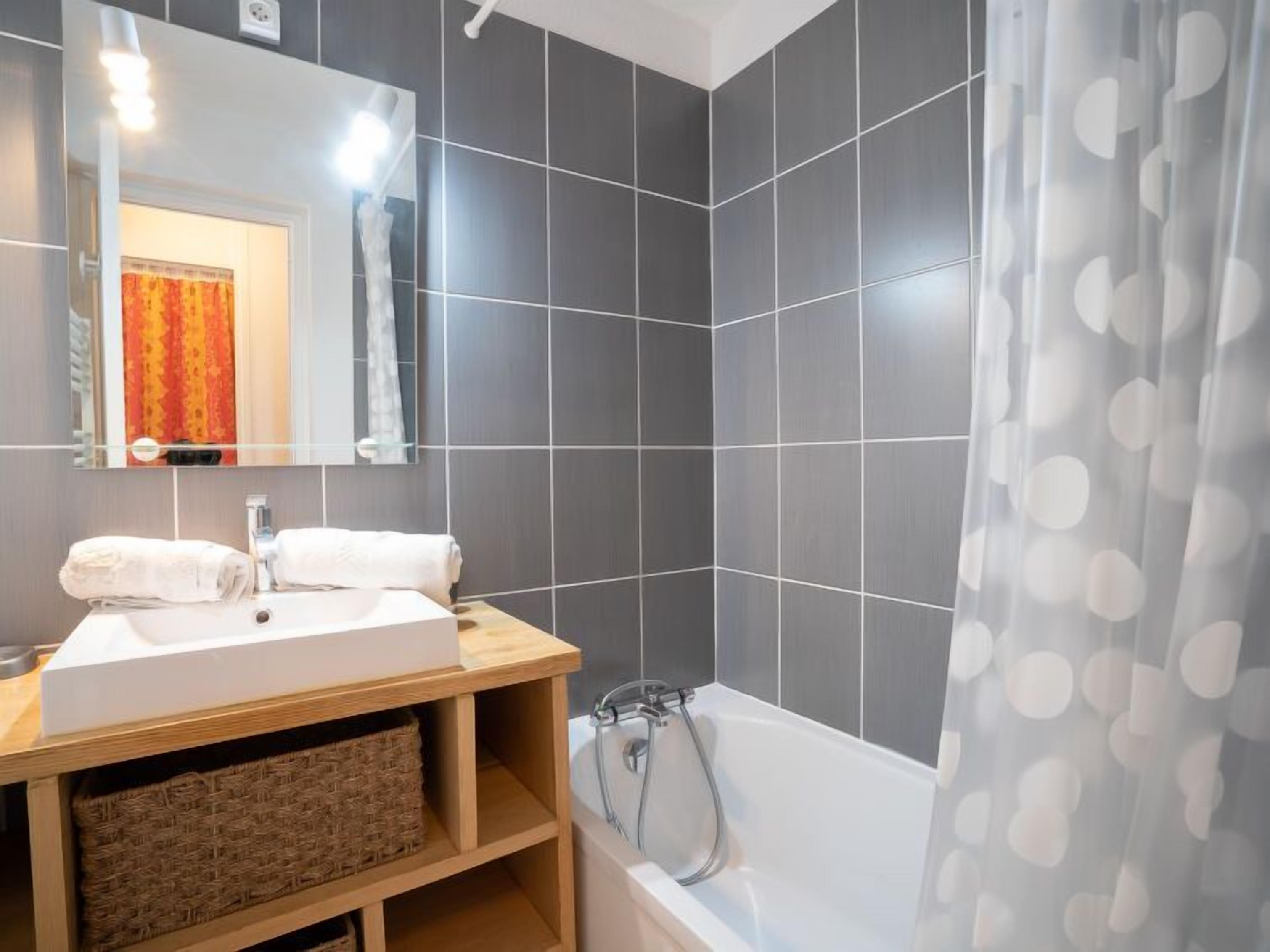 Une salle de bain moderne avec un lavabo blanc, un miroir et une baignoire.