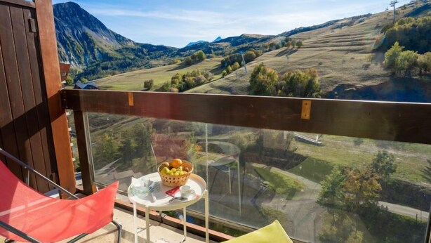 Un balcón con mesa, sillas y una cesta de fruta.