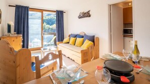 Una sala acogedora con sofá, mesa de comedor y sillas. Se ve una cocina a través de una puerta abierta.