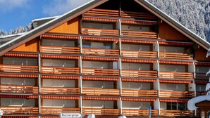 Un hotel de varios pisos con techo inclinado, balcones con barandillas de madera y un letrero que dice "Roche grise".