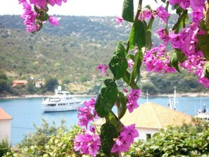 A coastal view with a boat in the background and pink flowers in the foreground. - Romantic apartment with sea view Vinišće, Dalmatia (Vinišće)