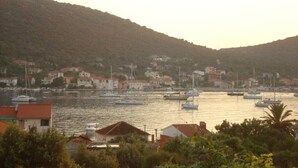 Une ville côtière où des bateaux sont amarrés dans le port, entourée de collines et d’immeubles d’habitation.