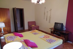 A bedroom with a bed, a television, a chair, and a wardrobe. - Romantic apartment with sea view Vinišće, Dalmatia (Vinišće)