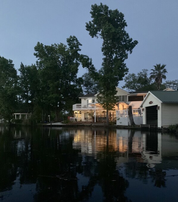 Une propriété située au bord de l’eau, avec une maison dotée d’un balcon et d’un quai.