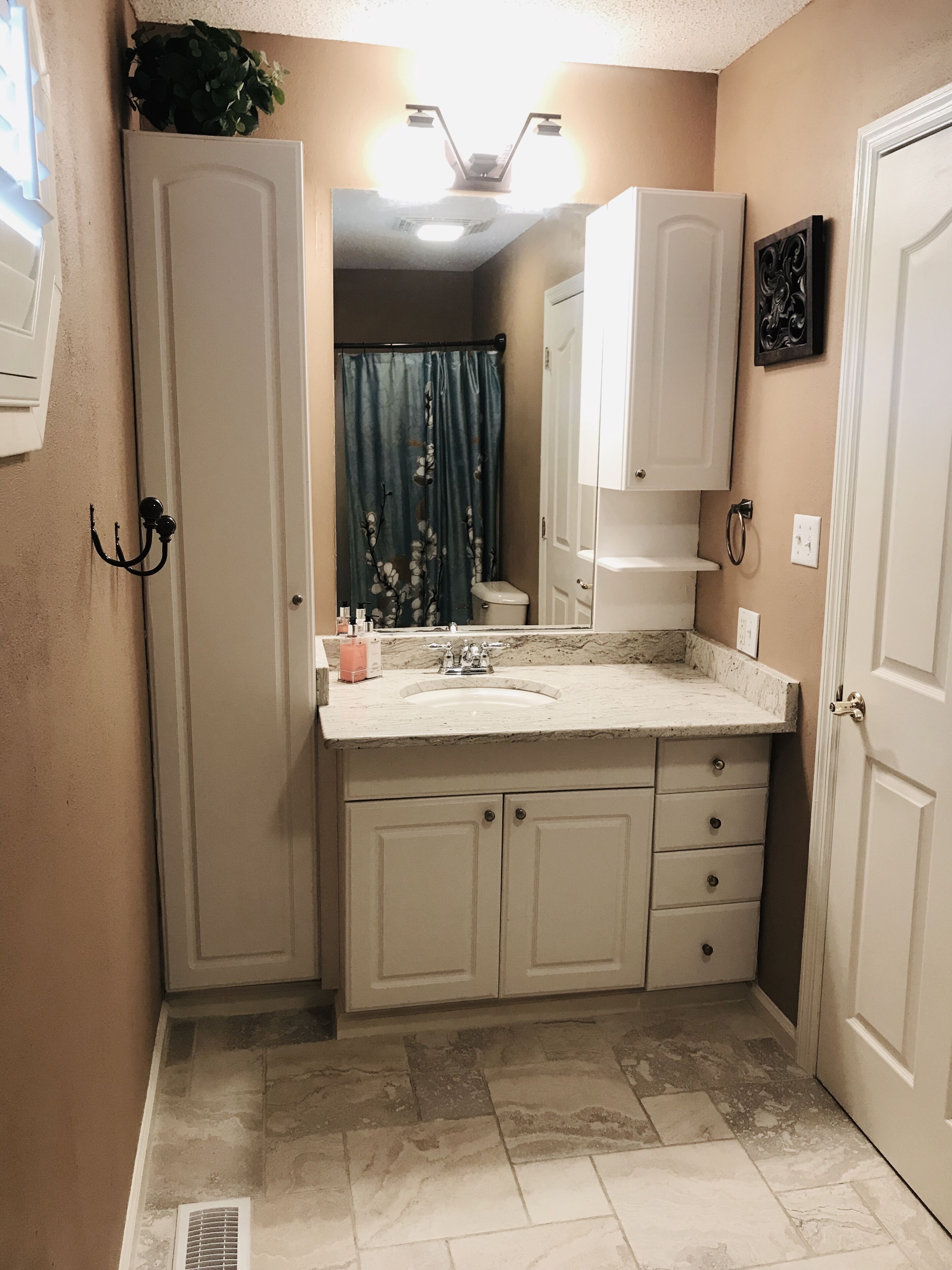 Une salle de bain équipée d’un lavabo, d’un miroir, de placards et d’un rideau de douche.