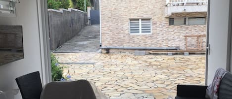 A covered patio area with stone flooring, a black sofa, and a table.