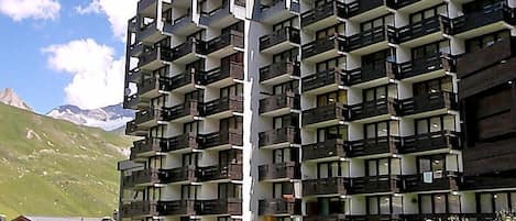 Ein mehrstöckiges Hotel mit Balkonen vor einer gebirgigen Kulisse.