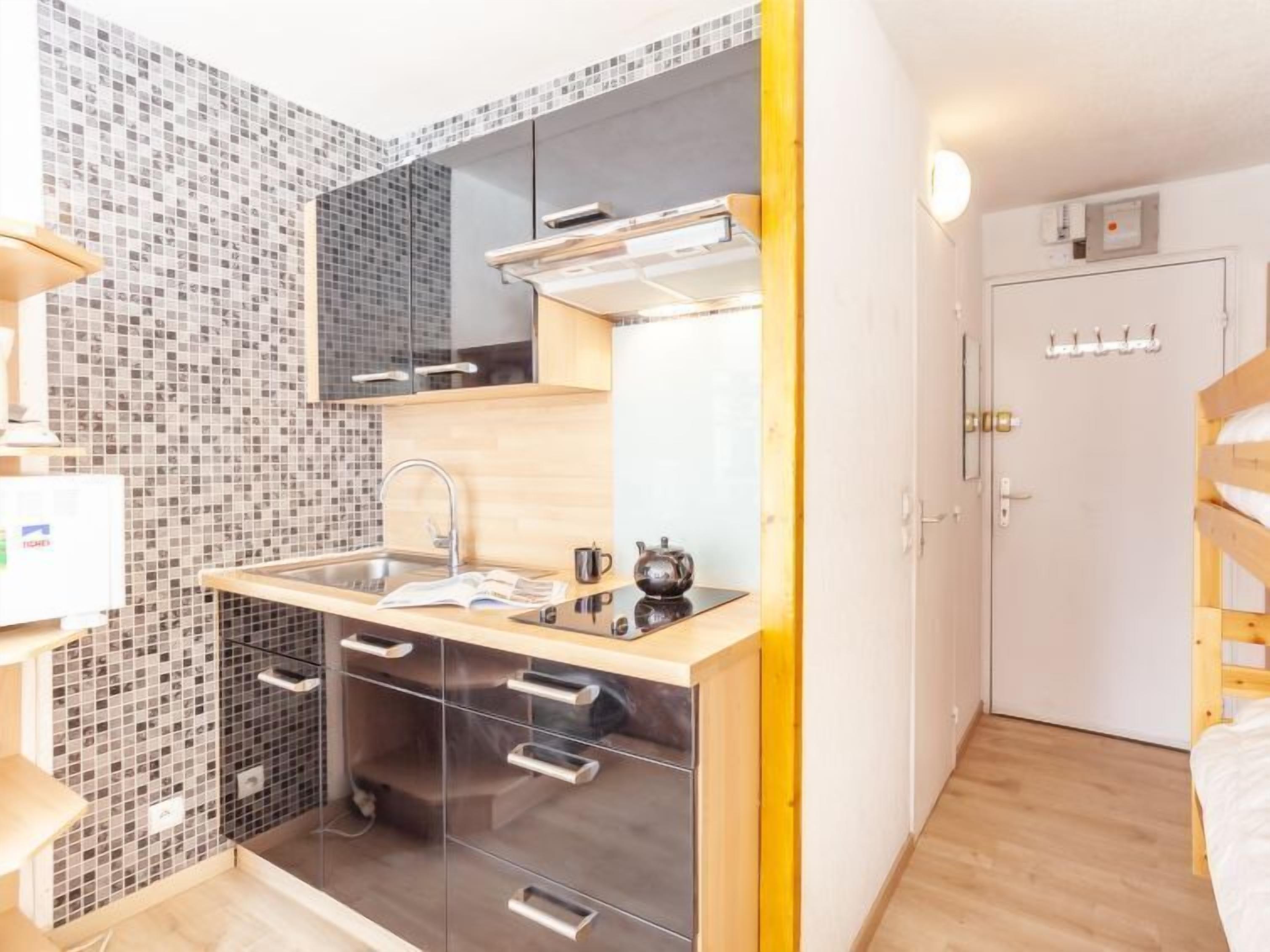 A compact kitchen with a sink, cabinets, and a microwave.