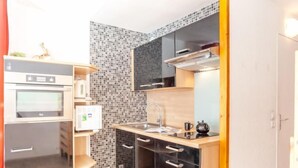 Une cuisine compacte équipée d’un four à micro-ondes, d’une bouilloire et d’un petit réfrigérateur.