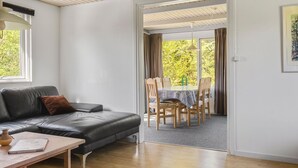 Una sala de estar moderna con un sofá de cuero, una mesa de centro de madera y un comedor con una mesa y sillas.