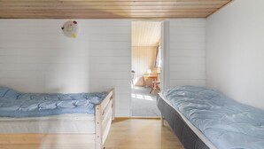 Una habitación con dos camas, suelo de madera y techo de madera, además de una ventana.