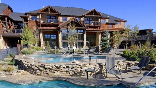 A resort with a pool area, lounge chairs, and a large building with multiple balconies. - Grand Timber One Bdr Master Full Kitchen Breckenridge, CO Ski-In/Out 5 Star (Breckenridge)