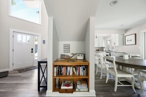 A modern kitchen with white cabinetry, a dining table with chairs, and a bookshelf with books and a Wi-Fi sign.