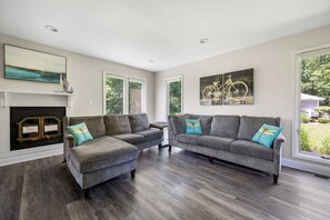 A living room with two grey sofas, a fireplace, and artwork on the walls. - Bethany Beach Getaway (Bethany Beach)