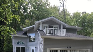 Una casa a due piani con garage, un portico e un piccolo balcone.