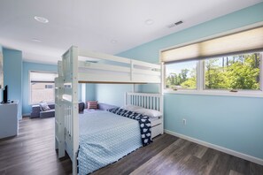 Ein Schlafraum mit Etagenbett, Fenster, Schreibtisch und Stuhl.