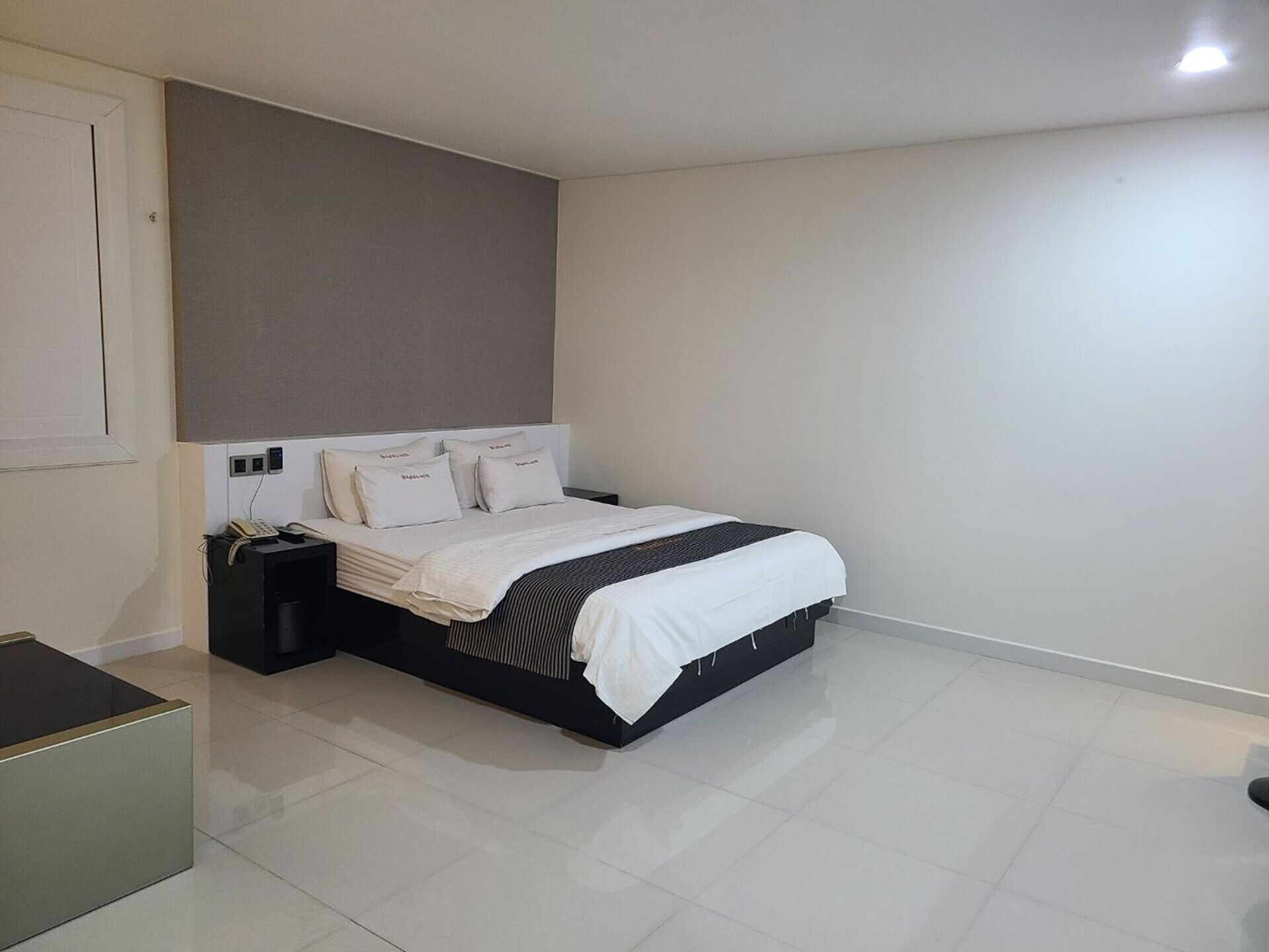 A bedroom with a bed, bedside tables, a nightstand, and a wall-mounted telephone.