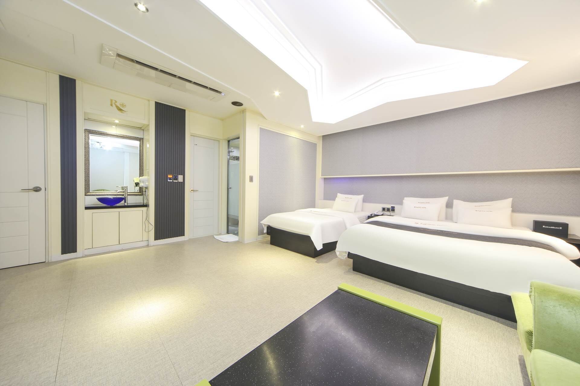 A modern hotel room with a large bed, a separate bathroom with a mirror, and a small seating area.
