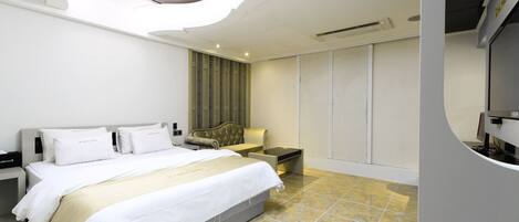 A modern hotel room with a bed, nightstands, a TV, and a wardrobe.