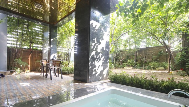 A modern outdoor pool area with a seating arrangement and a large water feature.