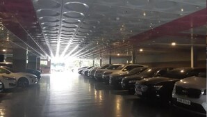 A parking garage with rows of parked cars and a ceiling with circular patterns.