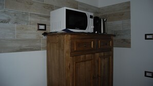 A microwave on a wooden cabinet in a kitchen with wooden wall tiles. - Dani's House (Cagliari)