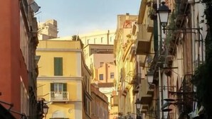 A narrow street lined with buildings, some with balconies and shops on the ground floor. - Dani's House (Cagliari)