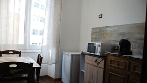 A compact kitchen with a refrigerator, microwave, and coffee maker on the counter. - Dani's House (Cagliari)