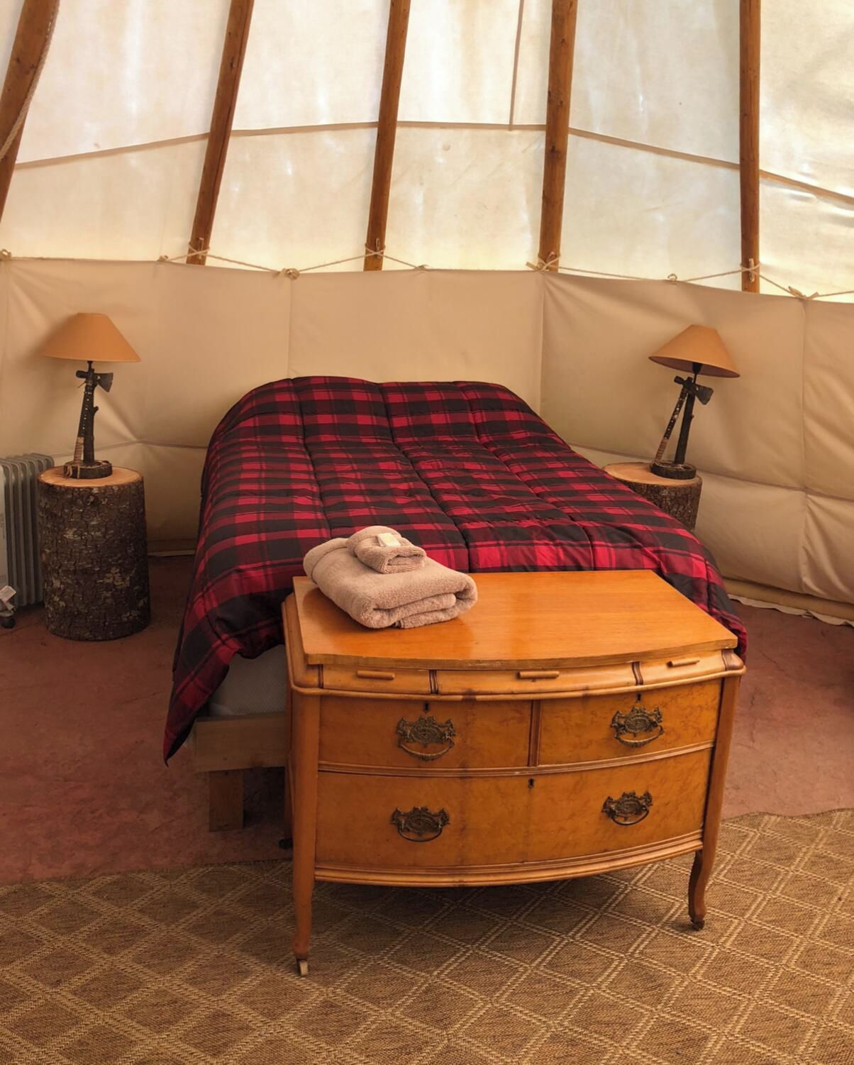 Une chambre avec un lit, une commode en bois et deux lampes.