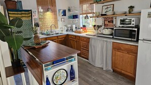A kitchen with wooden cabinets, a microwave, a coffee maker, and a pineapple on the counter. - 🦩Book Me Baby! Pool, Pet-Friendly Paradise Near Downtown Sarasota🦩 (Sarasota)
