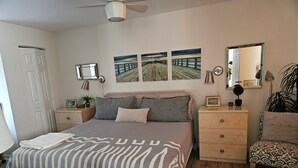 A bedroom with a bed, bedside tables, a dresser, a chair, a mirror, and artwork on the wall. - 🦩Book Me Baby! Pool, Pet-Friendly Paradise Near Downtown Sarasota🦩 (Sarasota)